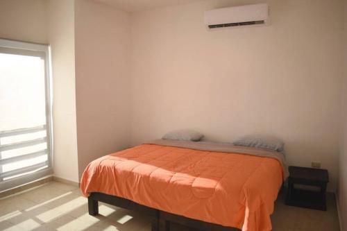 a bedroom with a bed with an orange blanket at 3 HABITACIONES, CERCA DE LA PLAYA, Cantera Residencial in San Carlos