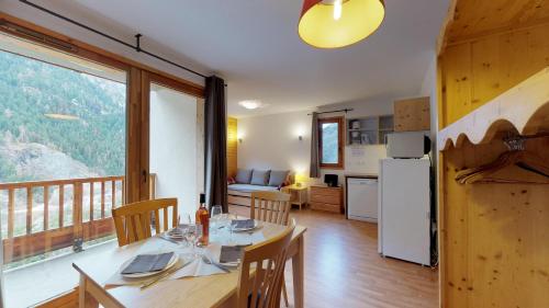 a dining room with a table and a kitchen with a balcony at Le Hameau SPA & PISCINE studio 4pers by Alpvision Résidences in Orelle