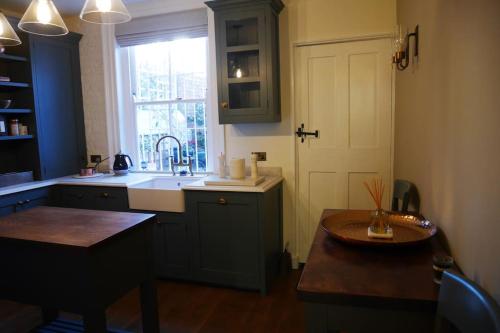 a kitchen with a sink and a door and a table at Luxury 2 bed Georgian Townhouse, Old Portsmouth in Portsmouth