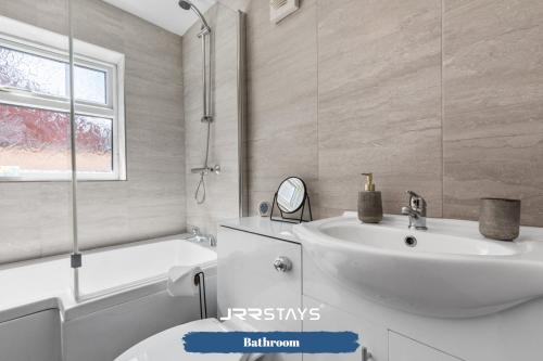 La salle de bains est pourvue d'un lavabo, de toilettes et d'une baignoire. dans l'établissement Nuneaton - Ideal 3 Bedroom, Wi-fi Parking, Sleeps 6 - JRR Stays, à Stockingford