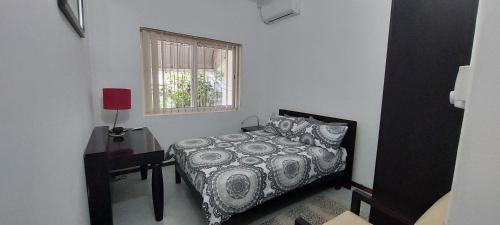 a bedroom with a bed and a table and a window at Lush Garden Villa with private pool in Trou aux Biches