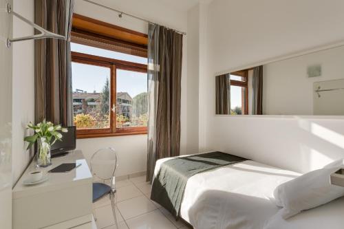 Schlafzimmer mit einem Bett, einem Schreibtisch und einem Fenster in der Unterkunft Hotel Darival Nomentana in Rom