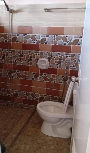 a bathroom with a brick wall next to a toilet at D&D Travellers INN in Puerto Princesa City