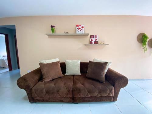 a brown couch sitting in a living room with pillows at Dois quartos com varanda - super espaçoso in Barra do Piraí