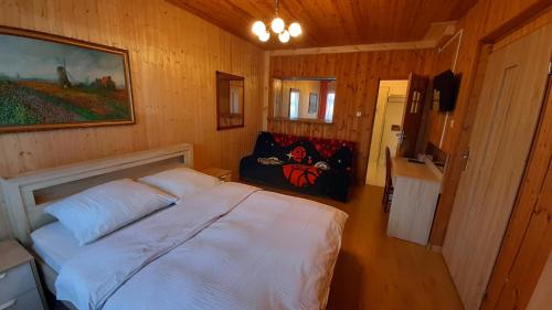 1 dormitorio con 1 cama blanca en una habitación de madera en Różana Karczma, en Kruszyn