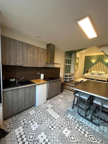 uma cozinha com uma mesa e um lavatório e uma cozinha com uma cama em La cabane verte - une nuit pour deux em Verneuil-sur-Vienne