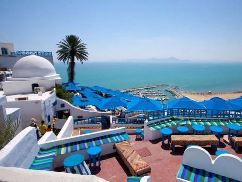 a view of the beach from a resort with blue umbrellas at Maison à El Omrane . in Tunis