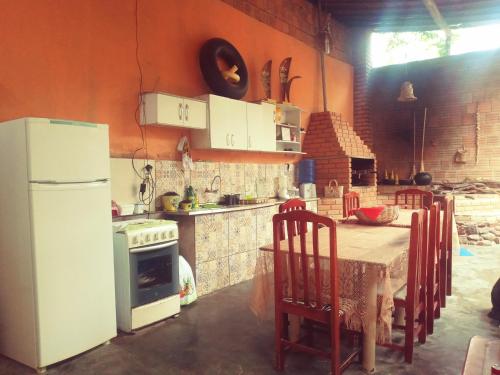 a kitchen with a table and a white refrigerator at Sítio Estrela da Manhã Hospedagem e Lazer in Palmeiras