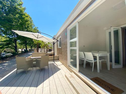 a deck with a table and chairs and an umbrella at Camping Village Mar y Sierra in San Costanzo