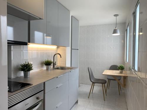 a kitchen with white cabinets and a sink and a table at Apartamento junto a Estación Ave · 3 dormitorios in Granada