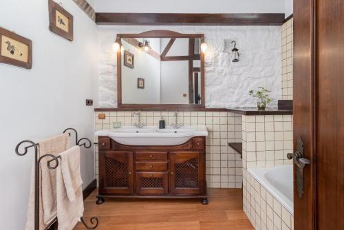 a bathroom with a sink and a tub and a mirror at Casa Camino del Dobra, Centro de Cantabria in Viérnoles