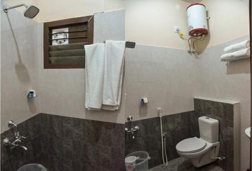 y baño con aseo, ducha y toallas. en Kumbakonam Inn Hotels - Kumbakonam Inn Stay, en Kumbakonam