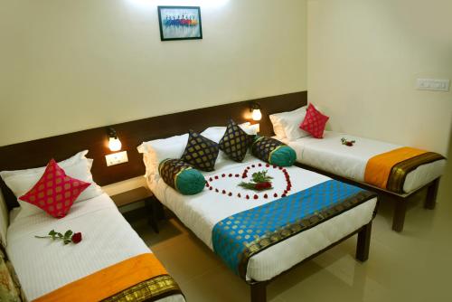 a room with two beds with colorful pillows at Kumbakonam Inn Hotels - Kumbakonam Inn Stay in Kumbakonam