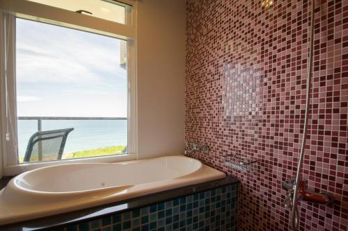 a bathroom with a bath tub and a window at Whitecaps B&B in Yanliau