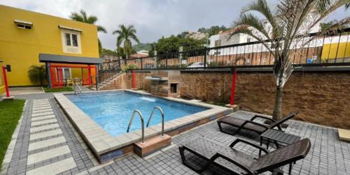 a swimming pool with chairs next to a building at Beverly Hills: Hotel and Business in San Salvador