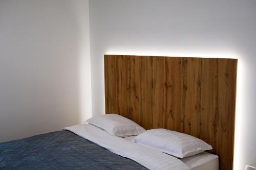 a bed with two pillows and a wooden headboard at Apartmaji 5KA in Velika Loka