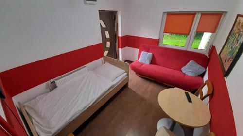 a small room with a red bed and a red couch at Różana Karczma in Kruszyn