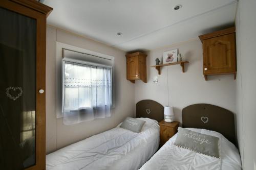 2 camas en una habitación pequeña con ventana en Mobil'home Les Pommes de Pin aux Mathes La Palmyre terrain privé, en Les Mathes