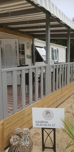 a porch with a white fence and a sign on it at Mobil'home proche du zoo de La Palmyre promotion séjour 2 jours in Les Mathes