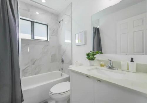 uma casa de banho branca com um WC, uma banheira e um lavatório. em Fantastic Brand New 3BD Duplex In Miami em Miami