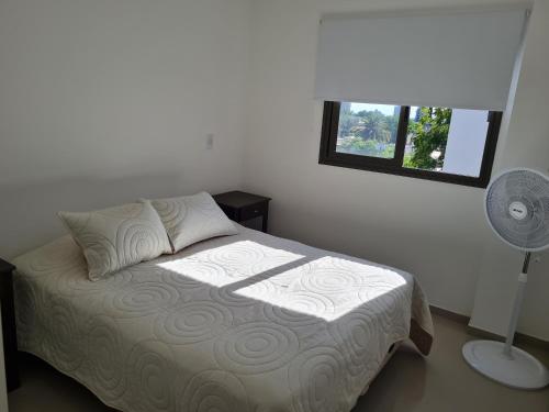 1 dormitorio con 1 cama con ventilador y ventana en Departamentos Mármol con Cochera en Godoy Cruz