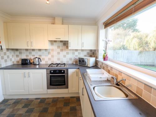 a kitchen with white cabinets and a sink and a window at Acre View in Mablethorpe