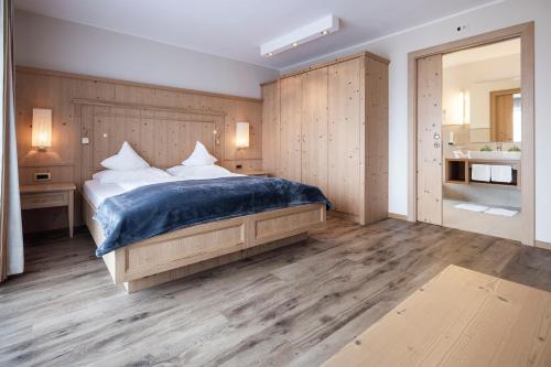 a bedroom with a large bed and a bathroom at Hotel Baumwirt in Castelrotto
