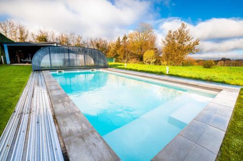 una piscina con una casa in vetro di Grande maison avec piscine et jacuzzi à la campagne a Desvres
