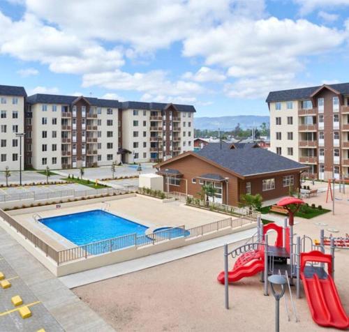an apartment complex with a pool and a playground at Acogedor departamento completamente equipado in Villarrica
