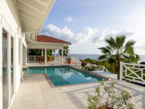 a house with a swimming pool and the ocean at Villa Happy View in Willibrordus