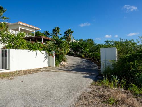 a driveway leading to a house with a white fence at Villa Happy View in Willibrordus