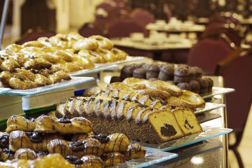 a bunch of different types of bread and pastries on trays at Anjum Makkah Hotel in Makkah