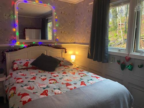 a bedroom with a bed with a christmas blanket and a mirror at Bluebell lodge in Fort William