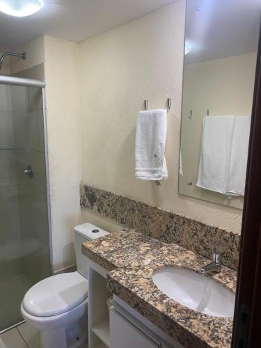 ein Badezimmer mit einem Waschbecken, einem WC und einem Spiegel in der Unterkunft Natal Plaza 604-Ponta Negra in Natal