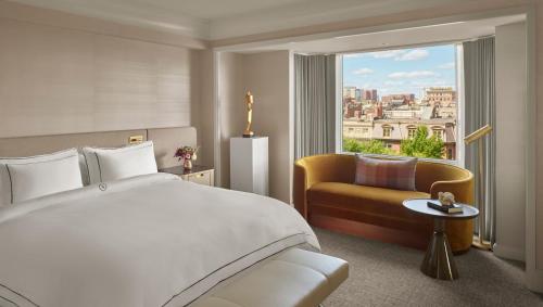 a bedroom with a bed and a couch and a window at The Newbury Boston in Boston