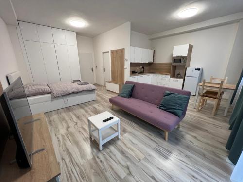 salon z fioletową kanapą i kuchnią w obiekcie Apartman Liptov NP14 w Liptowskim Mikulaszu