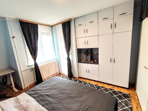 Un dormitorio con armarios blancos y una ventana grande. en Peti, en Belgrado