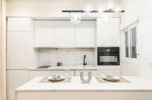 a kitchen with white cabinets and a table with wine glasses at NEW Sophisticated apartment with balcony & city views by REMS in Málaga