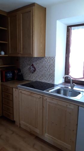 a kitchen with wooden cabinets and a sink and a window at CasaMau Bilo in Pera