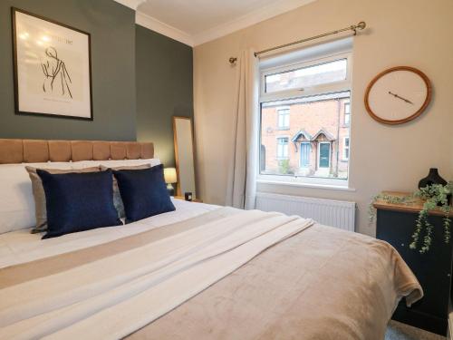 a bedroom with a bed with blue pillows and a window at The Crooked Cottage in Ashbourne