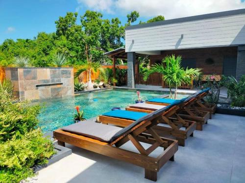 a row of chaise lounges next to a swimming pool at Villa Lou Santen Guadeloupe in Saint-François