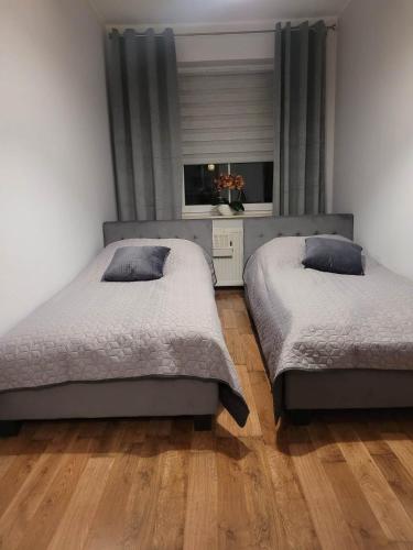 two beds in a bedroom with wooden floors at Apartament Grunwaldzka in Olecko