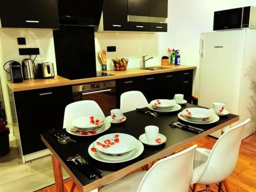 a kitchen with a table with white dishes on it at Chaleureuse Maisonnette Lyon in Meyzieu