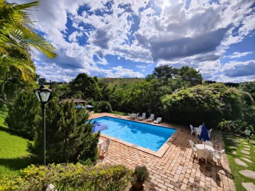 a swimming pool in a garden with a patio and trees at Chalés de Minas Hotel Fazenda in Caxambu