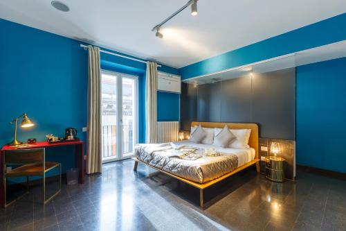 um quarto com paredes azuis, uma cama e uma secretária em Dimora Doria d'Angri em Nápoles