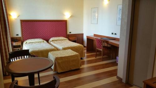 a hotel room with two beds and a table and a desk at Aretusa Palace Hotel in Syracuse