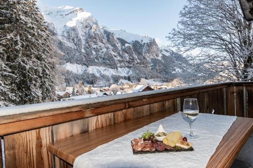 einen Tisch mit einem Teller Essen und einem Glas Wein in der Unterkunft Typically Swiss Hotel Ermitage in Kandersteg