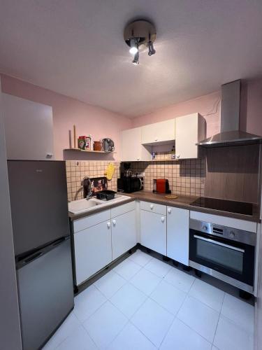 une cuisine avec des armoires blanches et des appareils noirs dans l'établissement Appartement 2 pièces meublés à Juan Les Pins, à Antibes