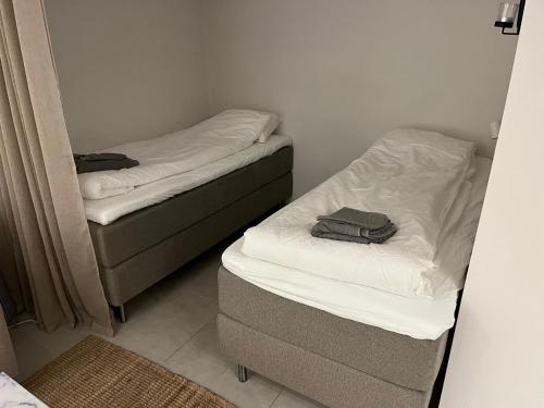 two twin beds in a small room with a mirror at Plomben B in Båstad