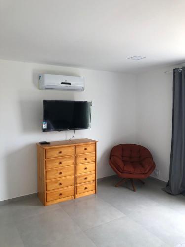 a living room with a television and a chair at Pousada Litorânea in Saquarema